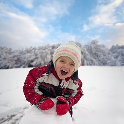 Portrait of child playing in snow with blurred background