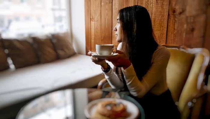 Picture of woman drinking coffee with selective blur in part of the picture
